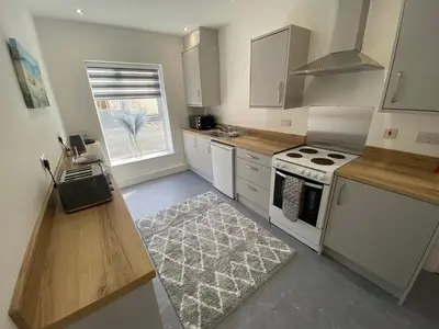 a kitchen with white cabinets and a stove top oven at Blackpool Abode - Silver Sands in Blackpool