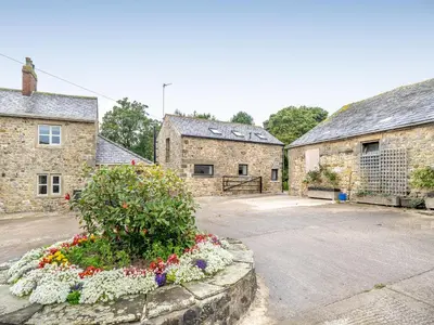 a courtyard of two stone buildings with a flower bed at The Granary in Inglewhite