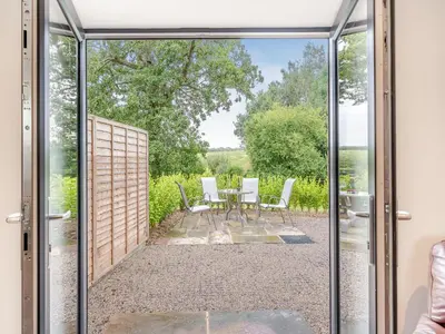 a sliding glass door leading to a patio with a table and chairs at The Granary in Inglewhite