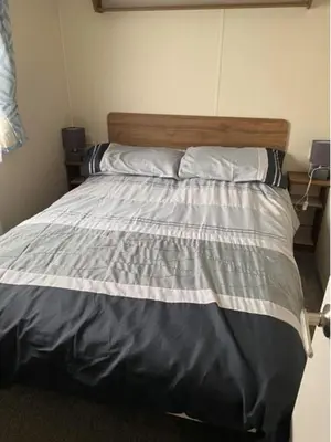 a bedroom with a bed with a striped comforter at Adams Caravan Holidays in Morecambe