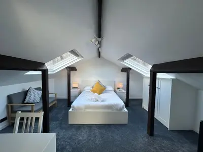 a attic bedroom with a bed and a chair at Sun Street Aparthotel in Lancaster