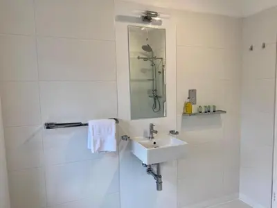 a white bathroom with a sink and a shower at Sun Street Aparthotel in Lancaster