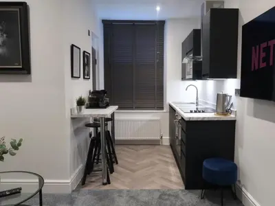 a kitchen with a sink and a counter with stools at Sun Street Aparthotel in Lancaster