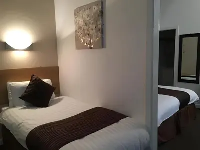 a hotel room with two beds and a mirror at Lord Nelson Hotel-Lime Street Station Liverpool by Compass Hospitality in Liverpool