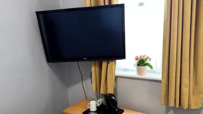 a flat screen tv sitting on a stand next to a window at Lord Nelson Hotel-Lime Street Station Liverpool by Compass Hospitality in Liverpool