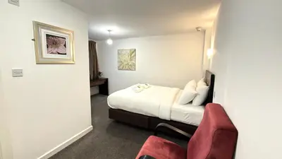 a hotel room with a bed and a red chair at Lord Nelson Hotel-Lime Street Station Liverpool by Compass Hospitality in Liverpool