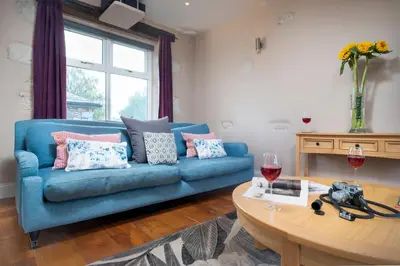 a living room with a blue couch and a table at Clare's Cottage Near Cartmel - Dog Friendly, Homely, Aga, Log Burners, Disney Plus & Netflix in Holker