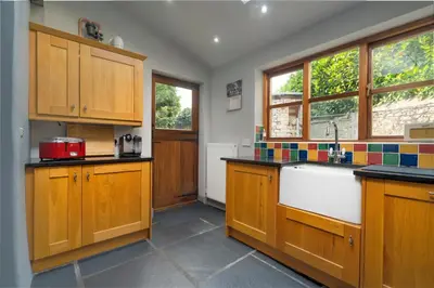 a kitchen with wooden cabinets and a sink at Clare's Cottage Near Cartmel - Dog Friendly, Homely, Aga, Log Burners, Disney Plus & Netflix in Holker