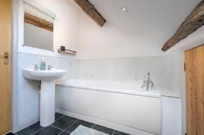 a bathroom with a white tub and a sink at Clare's Cottage Near Cartmel - Dog Friendly, Homely, Aga, Log Burners, Disney Plus & Netflix in Holker