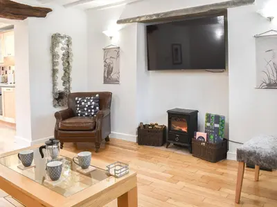 a living room with a chair and a fireplace at Thornton Cottage in Grizebeck