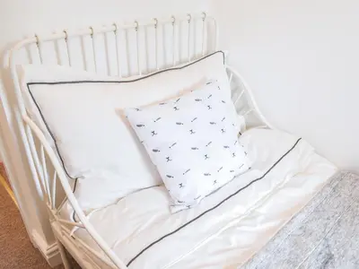 a white crib with a pillow on it at Thornton Cottage in Grizebeck