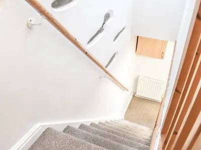 a staircase in a house with white walls at Thornton Cottage in Grizebeck
