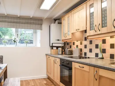 a kitchen with wooden cabinets and a window at Thornton Cottage in Grizebeck