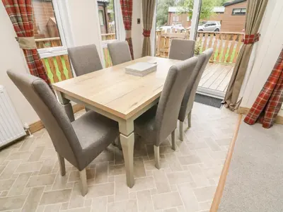 a wooden table and chairs in a room with a balcony at Coniston View 9 in Carnforth