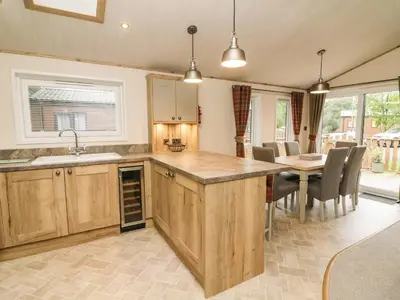 a kitchen with wooden cabinets and a table with chairs at Coniston View 9 in Carnforth
