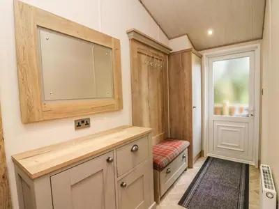 a bathroom with a large television and a red bench at Coniston View 9 in Carnforth