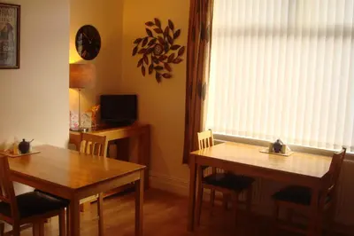 a dining room with two tables and a television at Wendover Guest House in Bolton