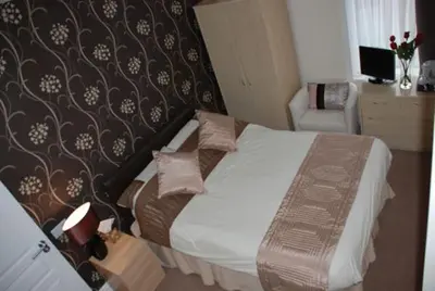 a hotel room with a bed and a chair at Wendover Guest House in Bolton
