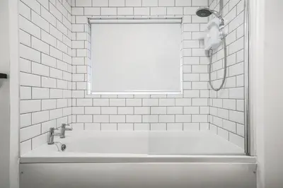 a white bathroom with a tub and a window at The Anfield Hotel in Liverpool