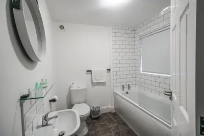 a white bathroom with a toilet and a tub and a sink at The Anfield Hotel in Liverpool