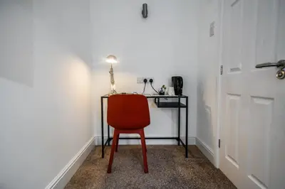 a red chair sitting in a room with a desk at The Anfield Hotel in Liverpool