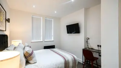 a white bedroom with a bed and a television at The Anfield Hotel in Liverpool