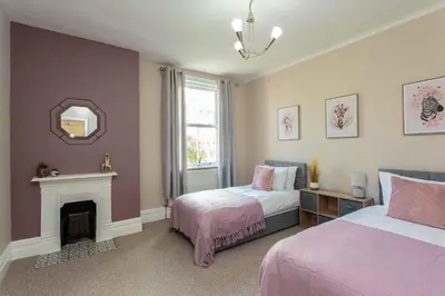 a bedroom with two beds and a fireplace and a mirror at Orchard Lodge in Lytham St Annes
