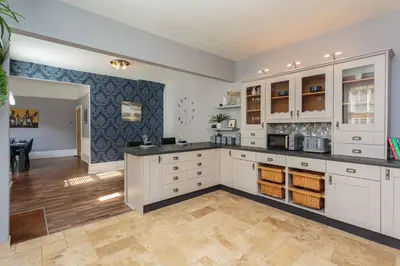 a large kitchen with white cabinets and a hardwood floor at Orchard Lodge in Lytham St Annes