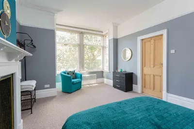 a bedroom with a blue bed and a blue chair at Orchard Lodge in Lytham St Annes