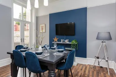 a dining room with a black table and blue chairs at Orchard Lodge in Lytham St Annes