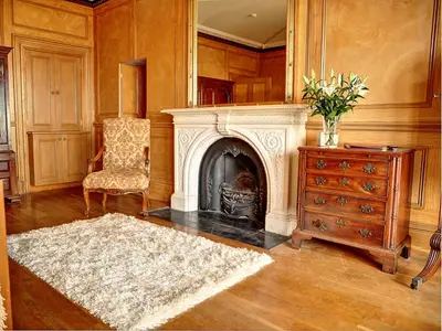 a living room with a fireplace and a chair and a dresser at Bay Villa in Grange Over Sands