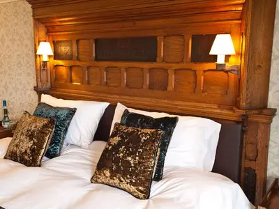 a bed with a wooden head board with pillows on it at Bay Villa in Grange Over Sands