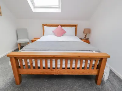 a bedroom with a wooden bed with a pink pillow at Sea La Vie in Lytham St Annes