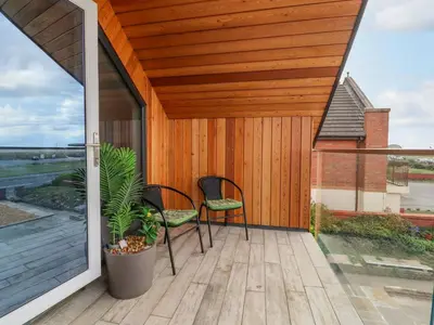 a patio with two chairs and a wooden deck at Sea La Vie in Lytham St Annes