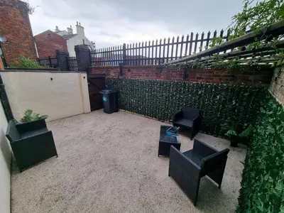 a small courtyard with chairs and a fence at Spacious 2 bed appartment next to BAE with spa bath in Barrow in Furness