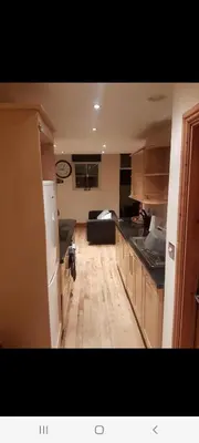 a kitchen with a refrigerator and a couch in a room at Spacious 2 bed appartment next to BAE with spa bath in Barrow in Furness