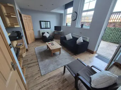 a living room with a couch and a table at Spacious 2 bed appartment next to BAE with spa bath in Barrow in Furness
