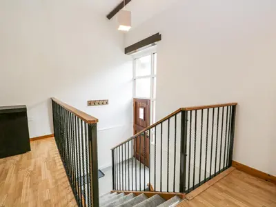 a staircase in an apartment with white walls and wooden floors at Coach House in Carnforth