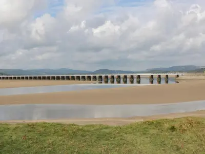 a bridge over a body of water next to a beach at Coach House in Carnforth
