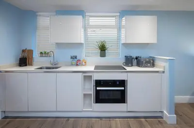 a kitchen with white cabinets and a sink at Coral Boutique Apartment 3 in Blackpool