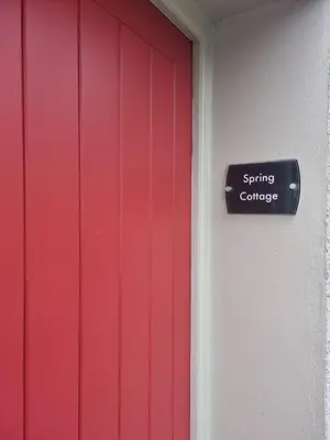 a red door with a sign that reads spring colleges at Spring Cottage in Ulverston