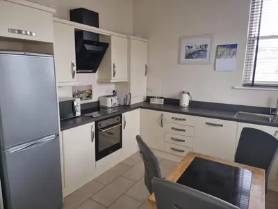 a kitchen with white appliances and a table and chairs at Spring Cottage in Ulverston