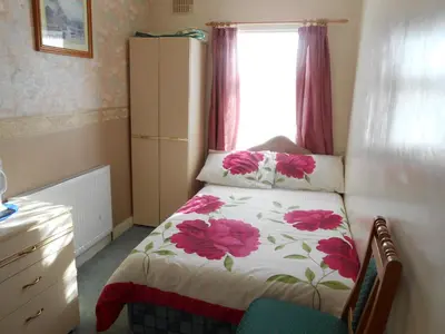 a small bedroom with a bed with pink flowers on it at The Lanes in Blackpool