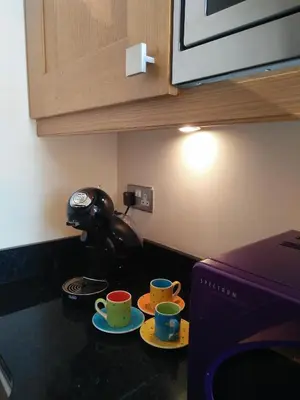 two cups on plates on a counter next to a coffee maker at The Shelbourne in Southport