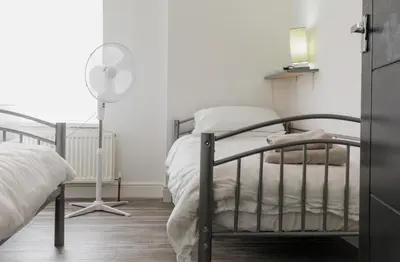 a bedroom with a bed and a floor fan at Windsor Stays 2 in Liverpool