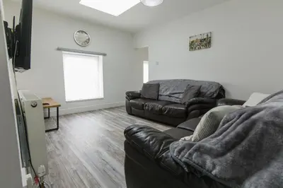 a living room with a leather couch and a television at Windsor Stays 2 in Liverpool