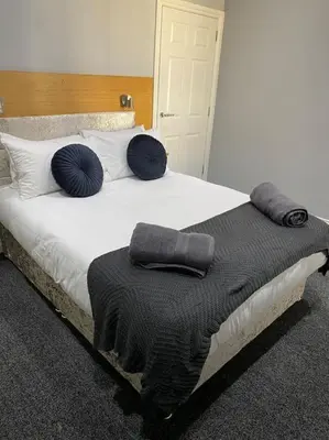 a bed with blue pillows and a black blanket on it at Velveteen by The V Group in Blackpool