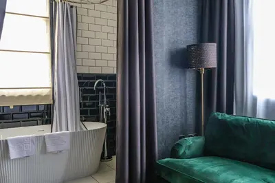 a bathroom with a bath tub and a green couch at 24 Catharine Street Hotel in Liverpool