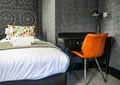 a bedroom with a bed and a chair next to a desk at 24 Catharine Street Hotel in Liverpool