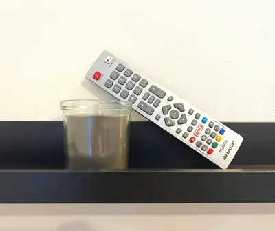 a remote control sitting next to a glass of milk at SA Stays in Wigan
